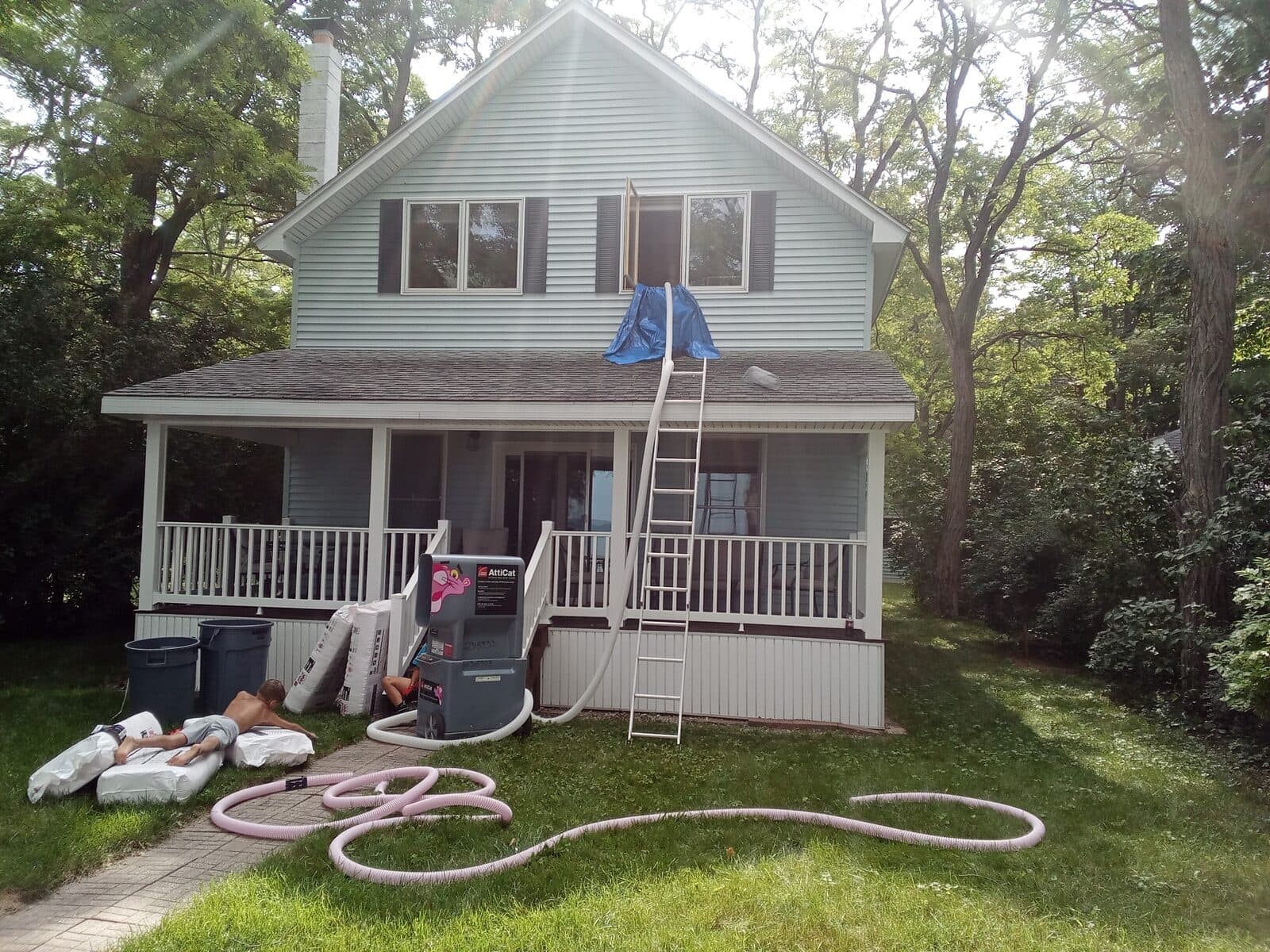 A Voss crew blowing fresh insulation into a two-story home through a hose run up a ladder