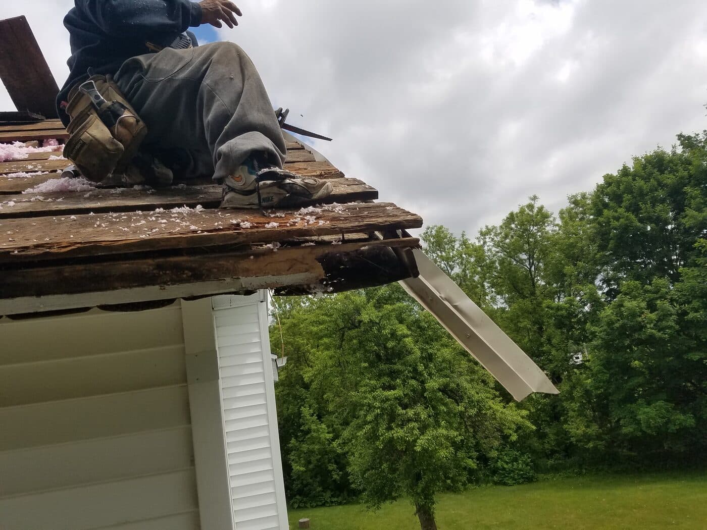 A technician on a roof edge repairing an opened fascia board